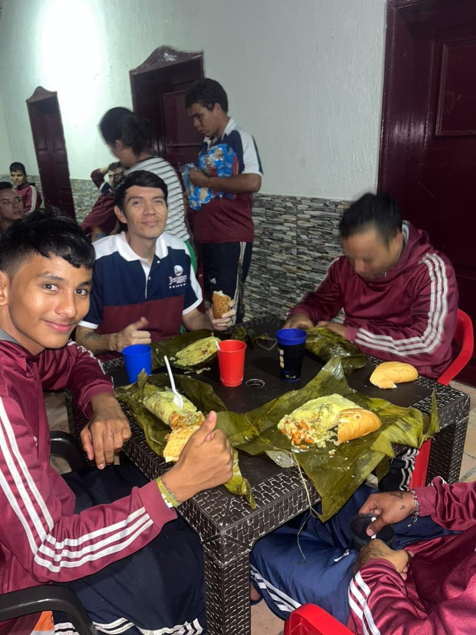 Table with food wrapped in leaves and bread during a shared meal