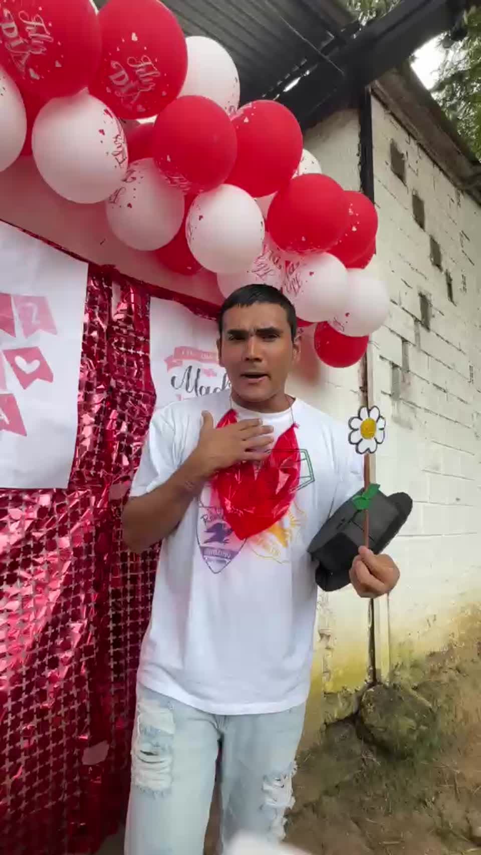 Participante sosteniendo una flor frente a decoración del Día de la Madre